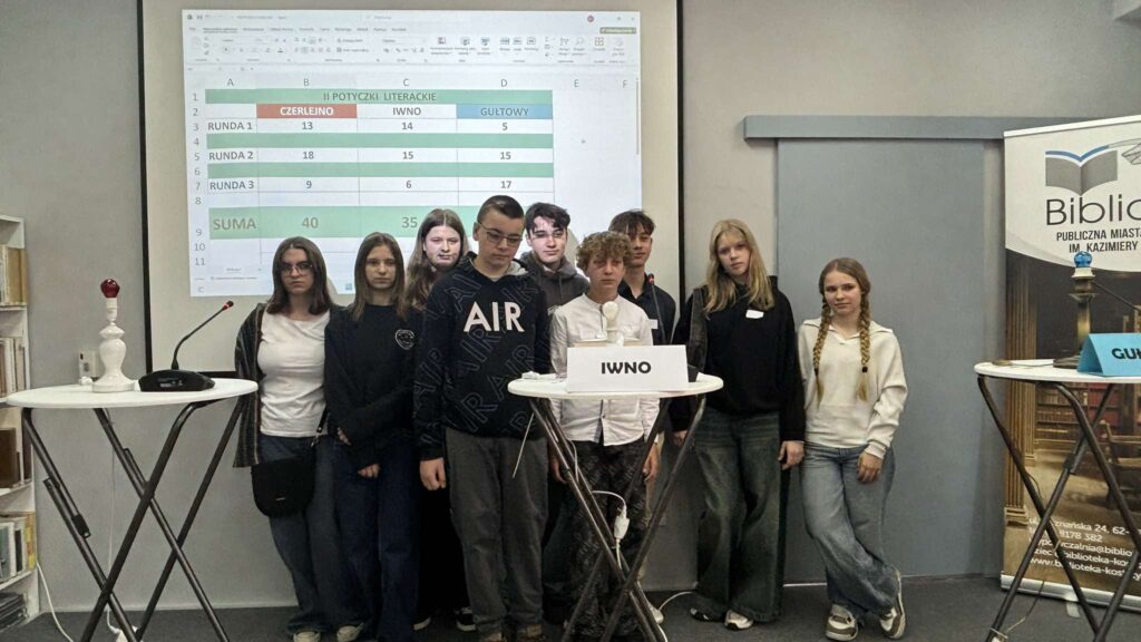 Na scenie stoi grupa uczniów z Iwna przy wysokim stoliku