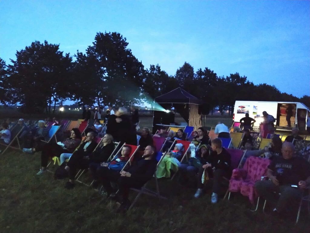 Publiczność na leżakach przed ekranem kina plenerowego