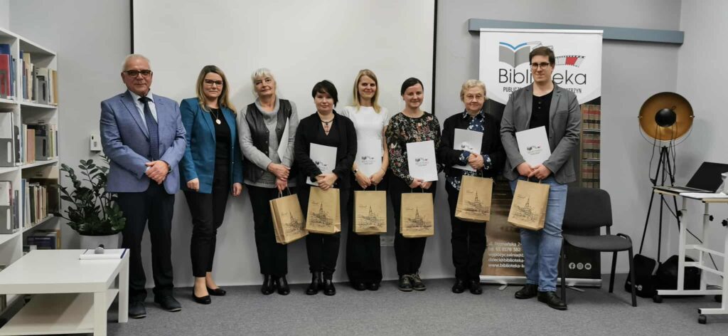 Kilkoro laureatów konkursu pozuje do zdjęcia. W rękach trzymają papierowe torebki.