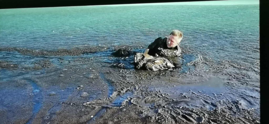 Zdjęcie przdstawia slajd, na którym mężczyzna ratuje orła z bagna.