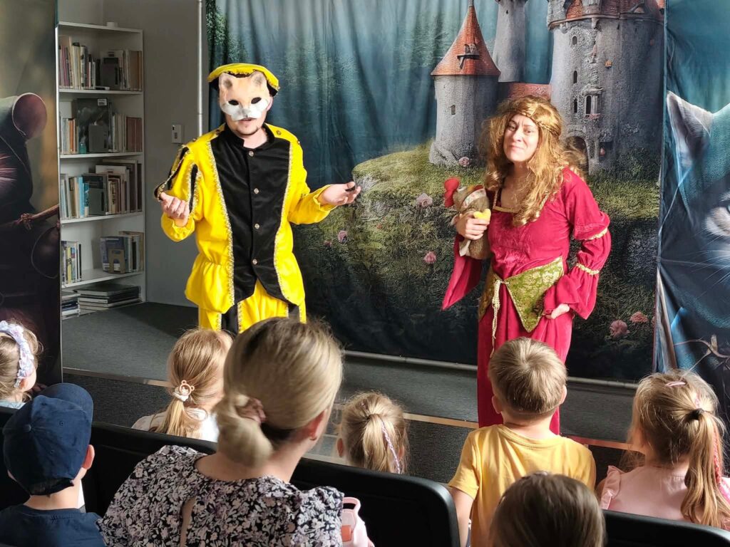 Dwoje aktorów w przebraniach występuje przed dziećmi.