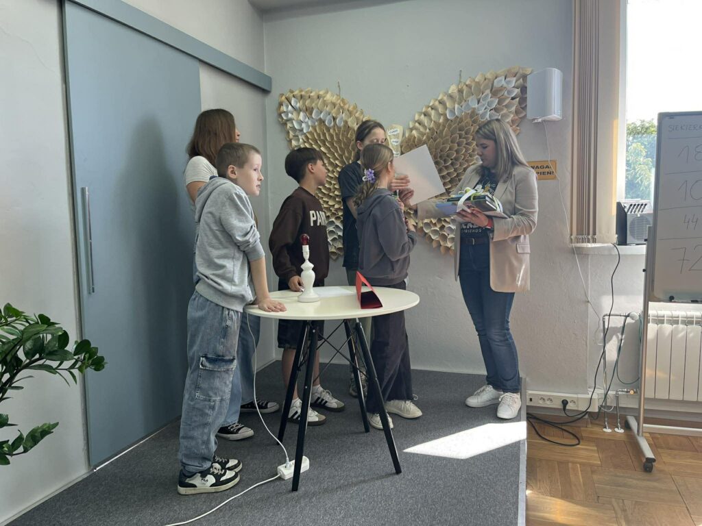 Dyrektor biblioteki wręcza nagrody książkowe pięciorgu uczniów.