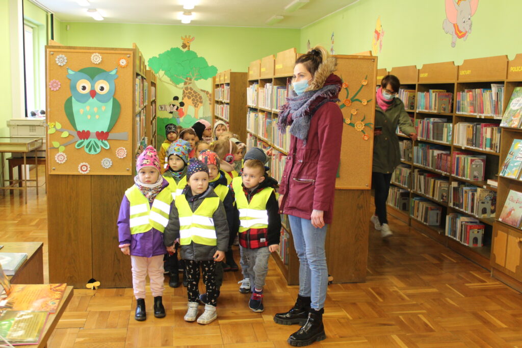 Grupa dzieci stoi między regałami z ksiązkami