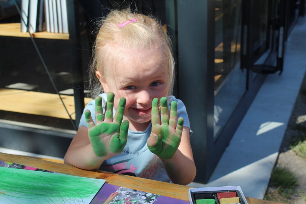Mała uczestniczka pleneru pokazuje pomalowane na zielono dłonie