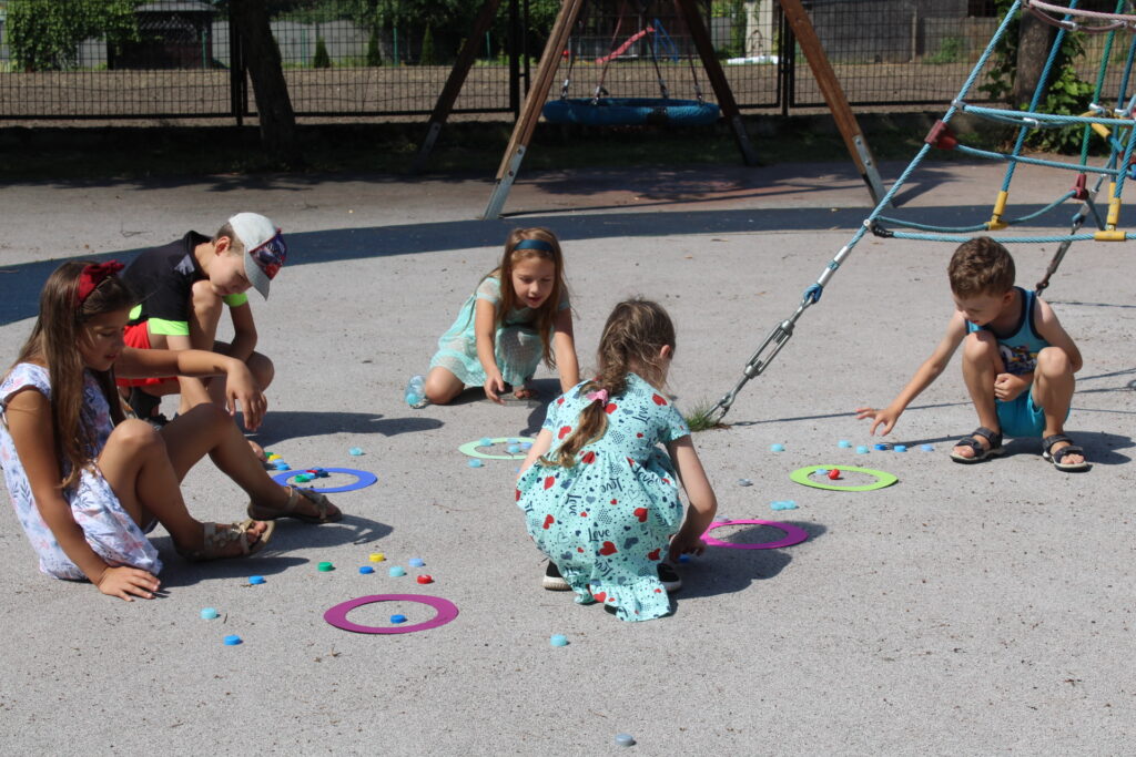Na placu zabaw przy szkole w Gułtowach kilkoro dzieci bawi się w "pchełki".