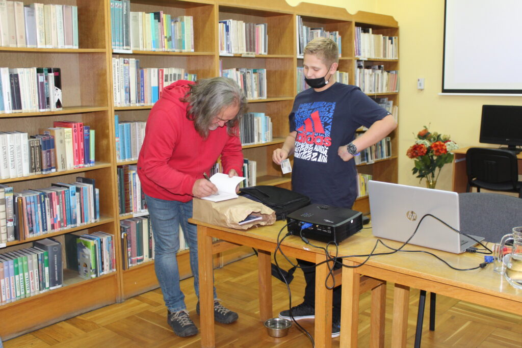 Krzysztof Nowakowski składa autograf w swej książce.