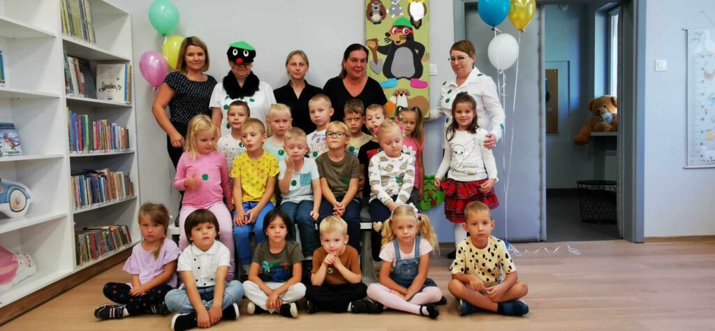 Grupa przedszkolaków wraz z paniami pozuje do zdjęcia w Oddziale dla Dzieci.