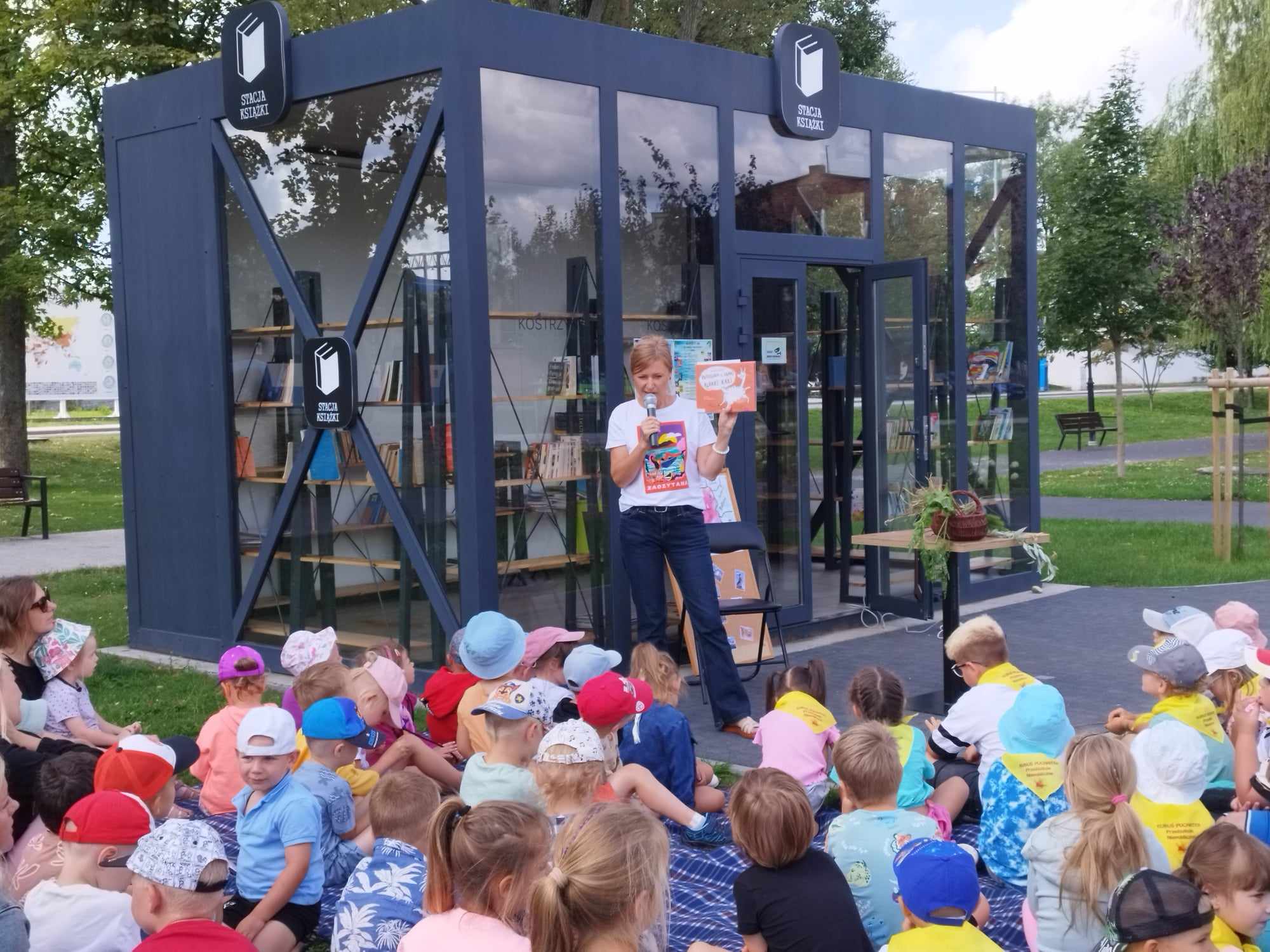 Przedszkolaki zgromadzone w parku przy Stacji Książki uczestniczą w Literackim Czwartku.