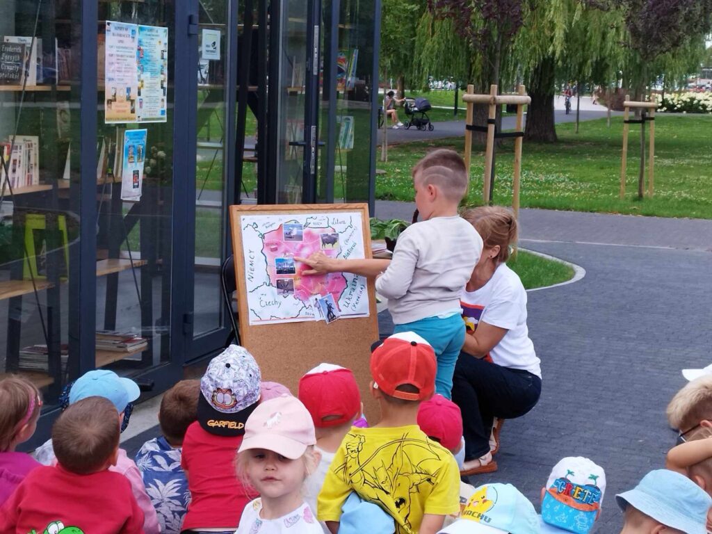 Przedszkolaki zgromadzone w parku przy Stacji Książki uczestniczą w Literackim Czwartku.