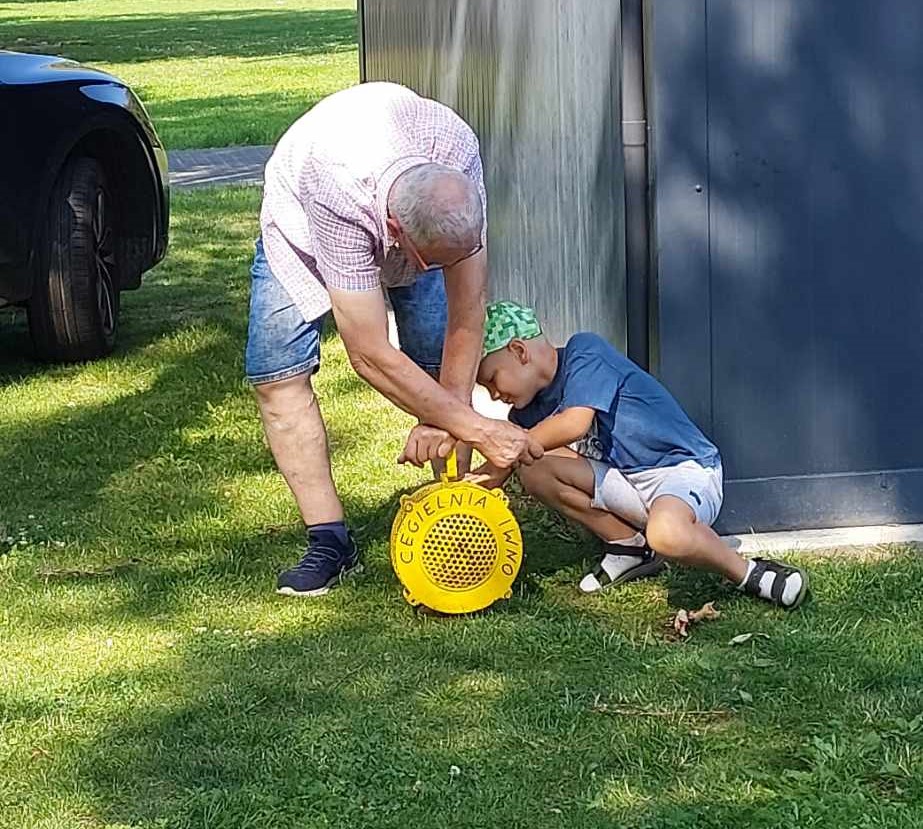 Zdjęcie przedstawia chłopca oraz mężczyznę obsługujących syrenę alarmową.